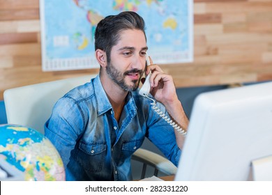 Smiling travel agent having phone call in the office
