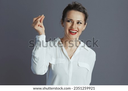 smiling trendy 40 years old business woman in white blouse fingers snapping isolated on grey background.
