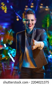 Smiling Trendy Female With Futuristic Goggles Giving Hand For A Handshake In Virtual Reality.