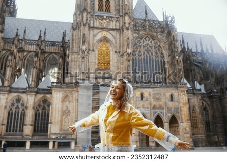 smiling trendy solo tourist woman in yellow blouse and raincoat in Prague Czech Republic sightseeing.
