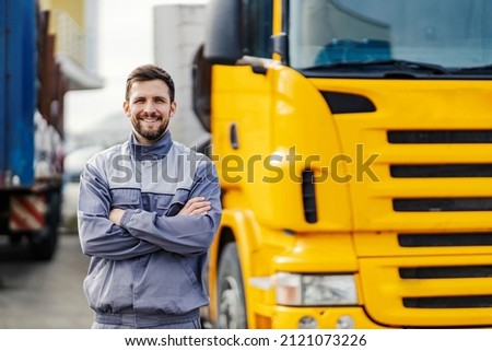 A smiling truck driver posing with trucks.