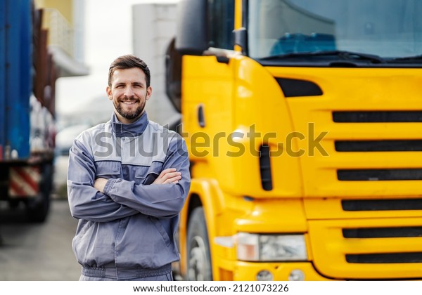 A smiling truck\
driver posing with trucks.