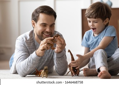 Smiling two generations male family resting on carpet floor, playing with dinosaurs toys together in living room. Happy young father enjoying playtime with joyful little school boy son at home. - Shutterstock ID 1646468758