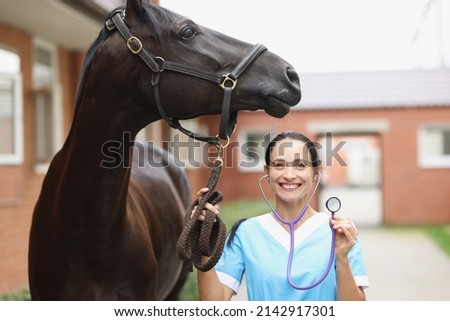 Smiling veterinarian with horse is holding stethoscope. Veterinary services concept