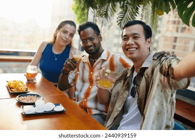 Smiling Vietnamese man taking selfie with best friends in bar - Powered by Shutterstock