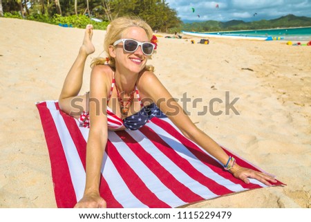 Smiling vintage 50s style woman, laying on american flag beach towel in Hawaiian tropical Lanikai Beach, with American flag bikini in Oahu island of Hawaii, USA. Freedom and 4th July patriotic concept