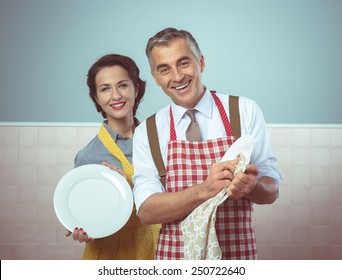 Smiling vintage couple in apron dish washing together