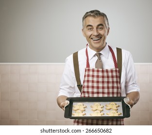 Smiling Vintage Man In Apron Cooking Delicious Gingerbread Men Cookies On A Baking Tray