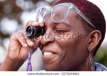 Smiling visually impaired woman using visually impaired tool to look across the street 