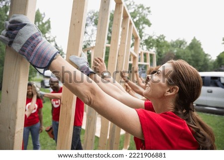 Smiling volunteers lifting construction frame