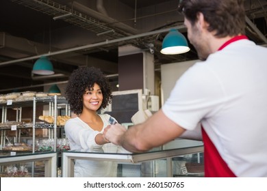 Smiling waiter doing transaction with customer at the bakery Foto Stock
