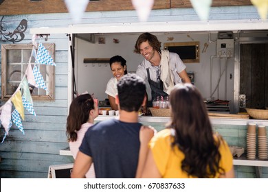 Smiling waiter giving order to customer at counter in food truck van - Powered by Shutterstock