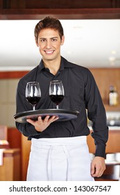 Smiling Waiter Serving Red Wine In A Restaurant