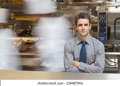 Smiling Waiter Standing In Busy Kitchen