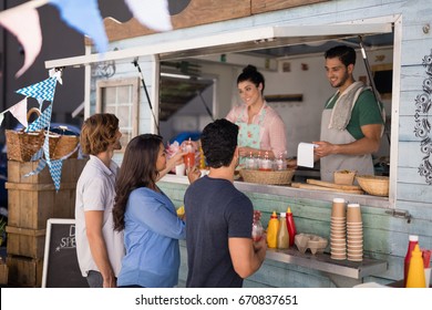 Smiling waiter taking order from customer at counter