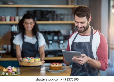 Smiling waiter using digital tablet at counter in caf\x92\xA9 - Powered by Shutterstock