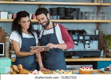 Smiling waiter and waitress using digital tablet at counter in cafÃ© - Powered by Shutterstock