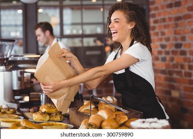 Smiling waitress giving paper bag to customer at coffee shop