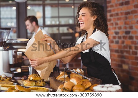Smiling waitress giving paper bag to customer at coffee shop