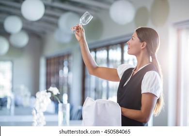 Smiling waitress holding up a empty wine glass in restaurant - Powered by Shutterstock