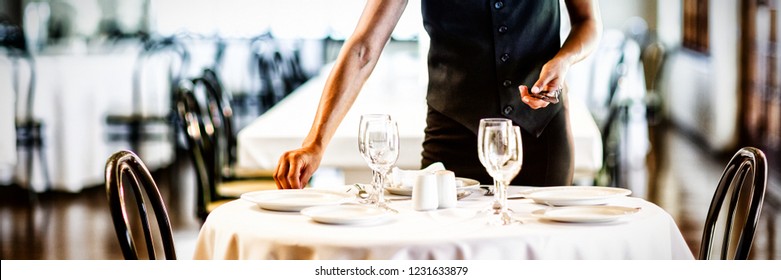 Smiling waitress setting the table in a restaurant - Powered by Shutterstock