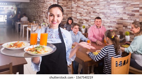 Smiling waitress warmly welcoming guests to comfortable family cafe