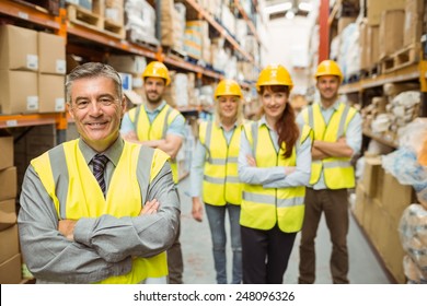 Smiling Warehouse Team With Arms Crossed In A Large Warehouse