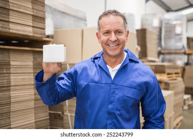 Smiling Warehouse Worker Holding Small Box In A Large Warehouse