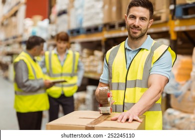 Smiling Warehouse Workers Preparing A Shipment In A Large Warehouse