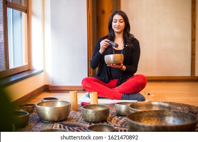 A Smiling Wellness Practitioner Uses An Ancient Tibetan Singing Bowl To Induce Feelings Of Relaxation And Healing In Her Clients. 