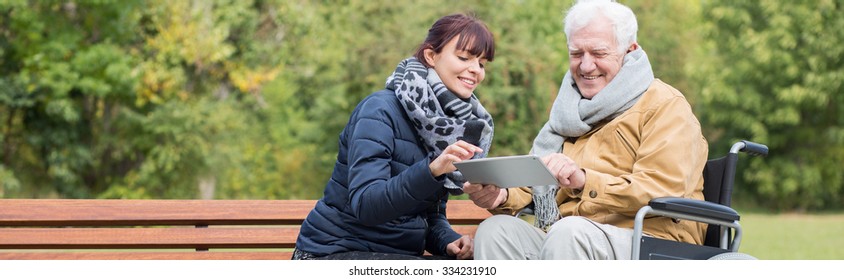 Smiling wheelchair man is using tablet outdoor - Powered by Shutterstock