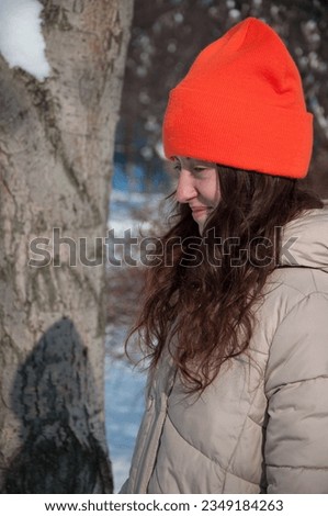 smiling winter girl in orange warm hat in snow wintertime. winter fashion of girl in warm hat with wintertime snow.