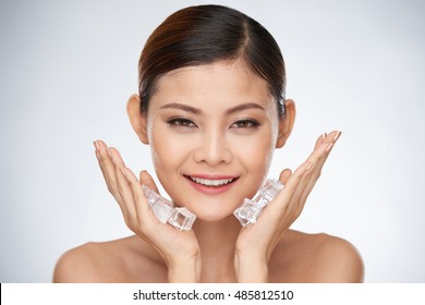 Smiling Woman Applying Ice Cube Treatment On Face