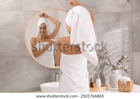 Smiling woman applying solid deodorant near mirror at home, back view