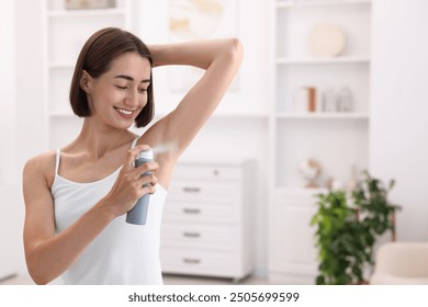 Smiling woman applying spray deodorant at home. Space for text