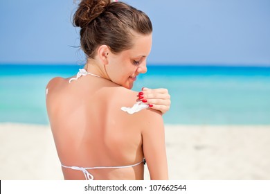 A Smiling Woman Is Applying Sunblock Near The Sea