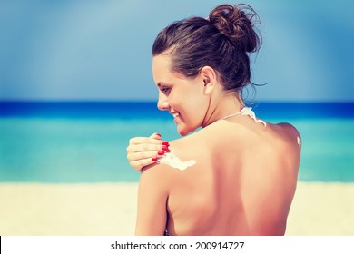 A Smiling Woman Is Applying Sunblock On The Beach, Vintage-style Photo.