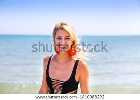 Smiling woman in black swimwear on the summer beach 