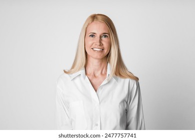 A smiling woman with blonde hair and wearing a white button-down shirt stands against a white background. Her bright white shirt has a collar and long sleeves - Powered by Shutterstock