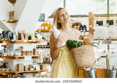 Smiling woman buying organic products in zero waste shop. Female customer makes thoughtful shopping in modern plastic free store. Concept of retail of eco food and conscious consumerism. - Powered by Shutterstock