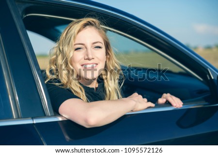 Smiling woman in the car on a summer day. Attractive blonde at the wheel of a car.