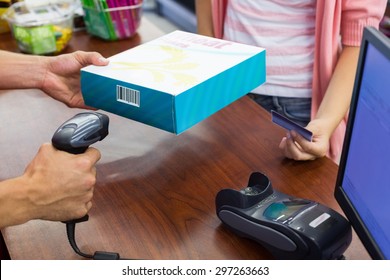 Smiling woman at cash register paying with credit card and scan a product in supermarket - Powered by Shutterstock