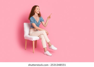 Smiling woman in casual attire pointing on pink background - Powered by Shutterstock