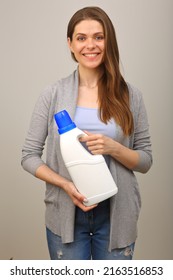 Smiling Woman In Casual Clothes Holding Laundry Detergent In White Bottle. Isolated Girl Portrait.