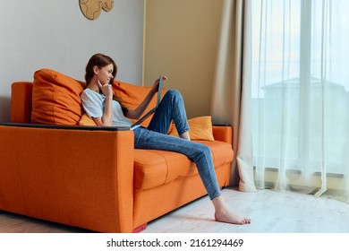 Smiling Woman Chatting On The Orange Couch With A Laptop Unaltered