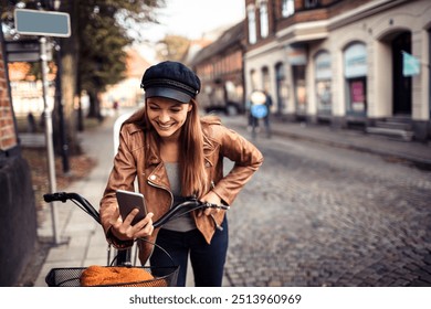 Smiling woman checking smartphone while holding bicycle on city street - Powered by Shutterstock