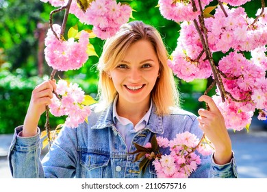 Smiling woman in cherry bloom. Girl with sakura. Springtime. Blossom season. Blooming sakura tree.