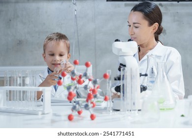 Smiling woman and child boy in lab coats working with molecular model, Science kids modern technology education concept,  - Powered by Shutterstock