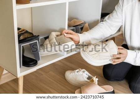 Smiling woman choosing footwear shoes closet comfortable storage contemporary organize at home. Female household cleaning maintaining footgear cupboard with shelves modern interior with potted plant
