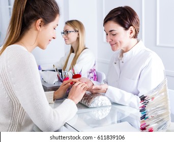 Smiling woman client having manicure done in nail salon
